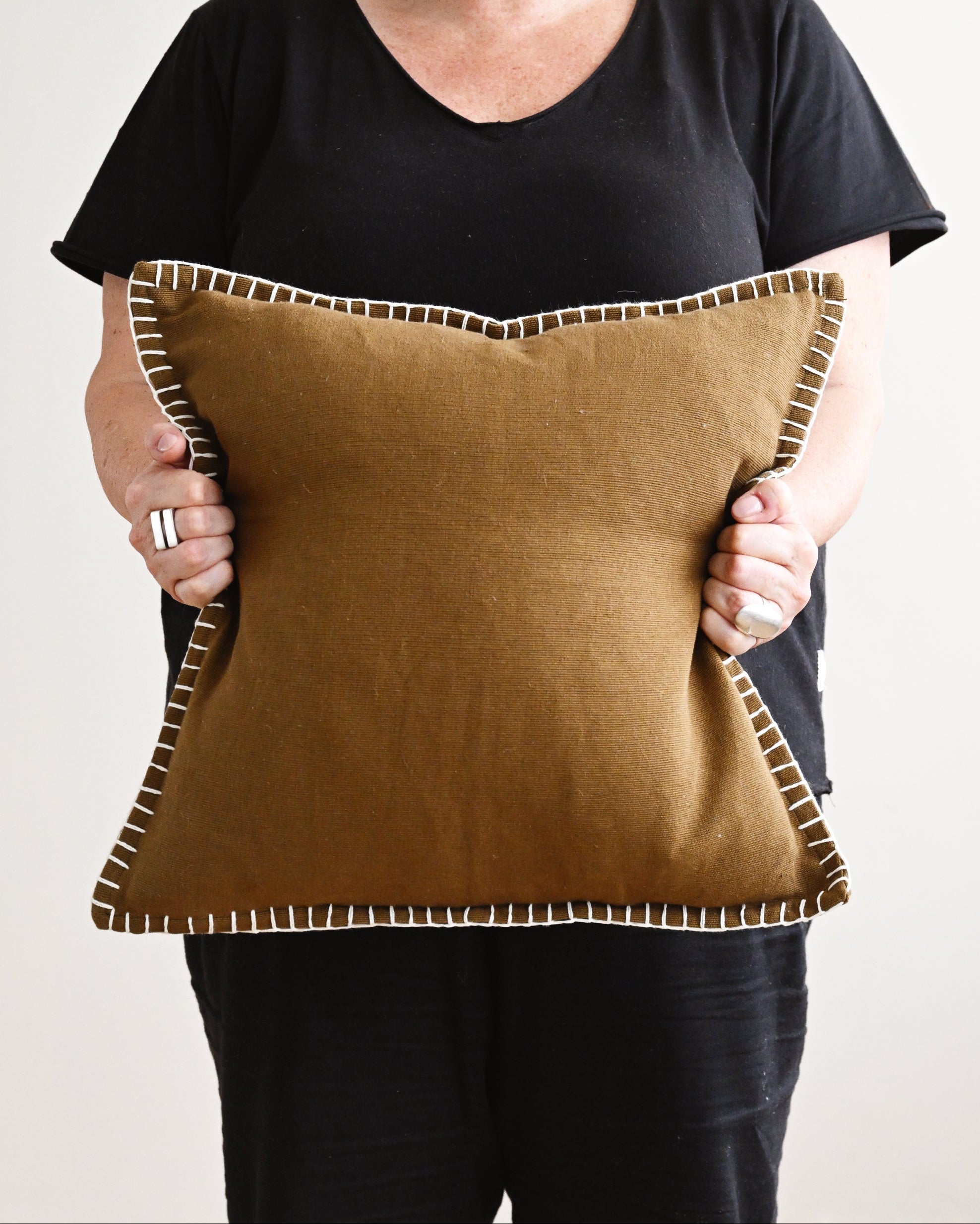 Person holding a brown pillow with a plain background
