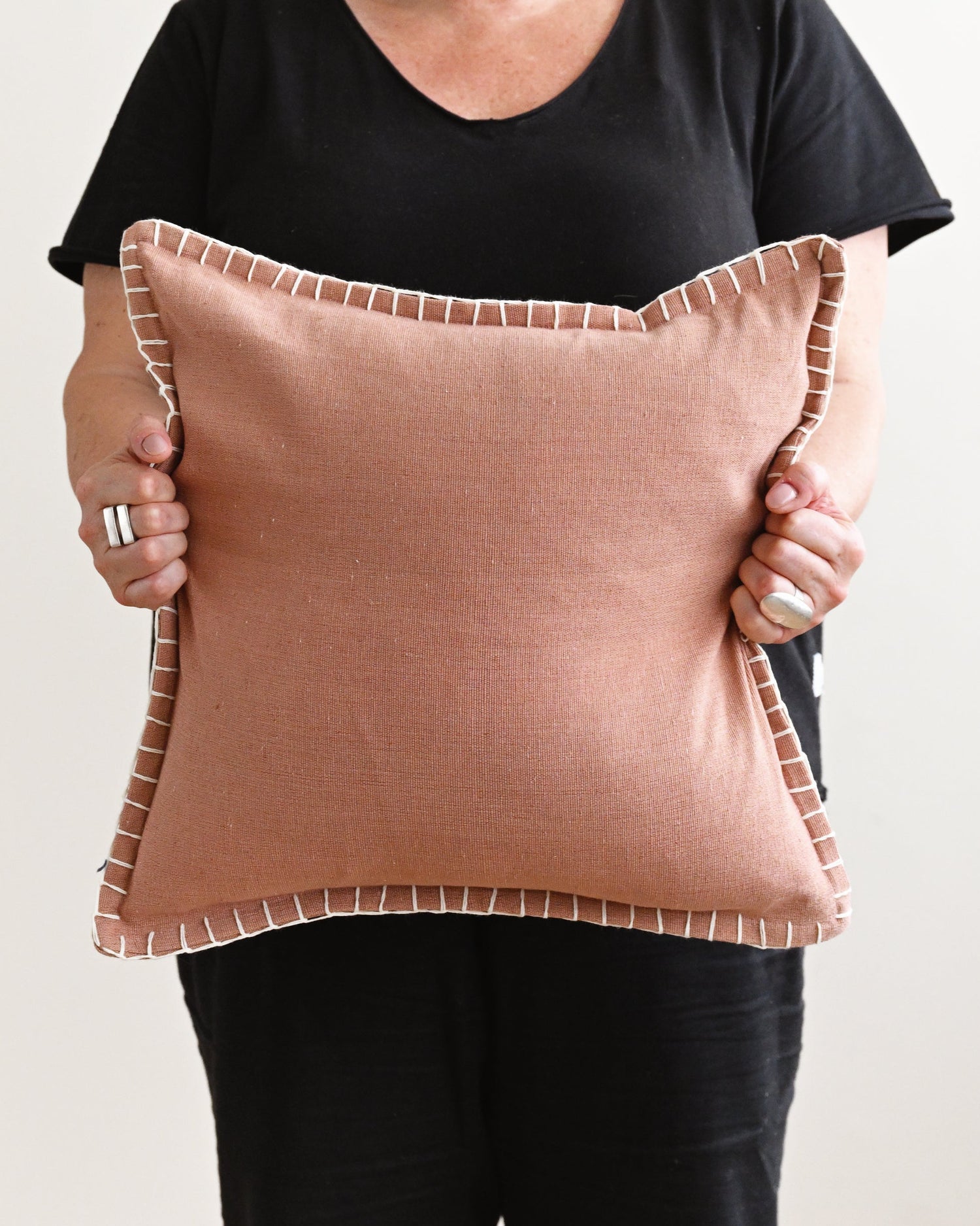 Person holding a pink pillow against a plain background