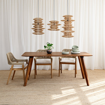 Dining area with wooden table and chairs under pendant lights in a bright room.