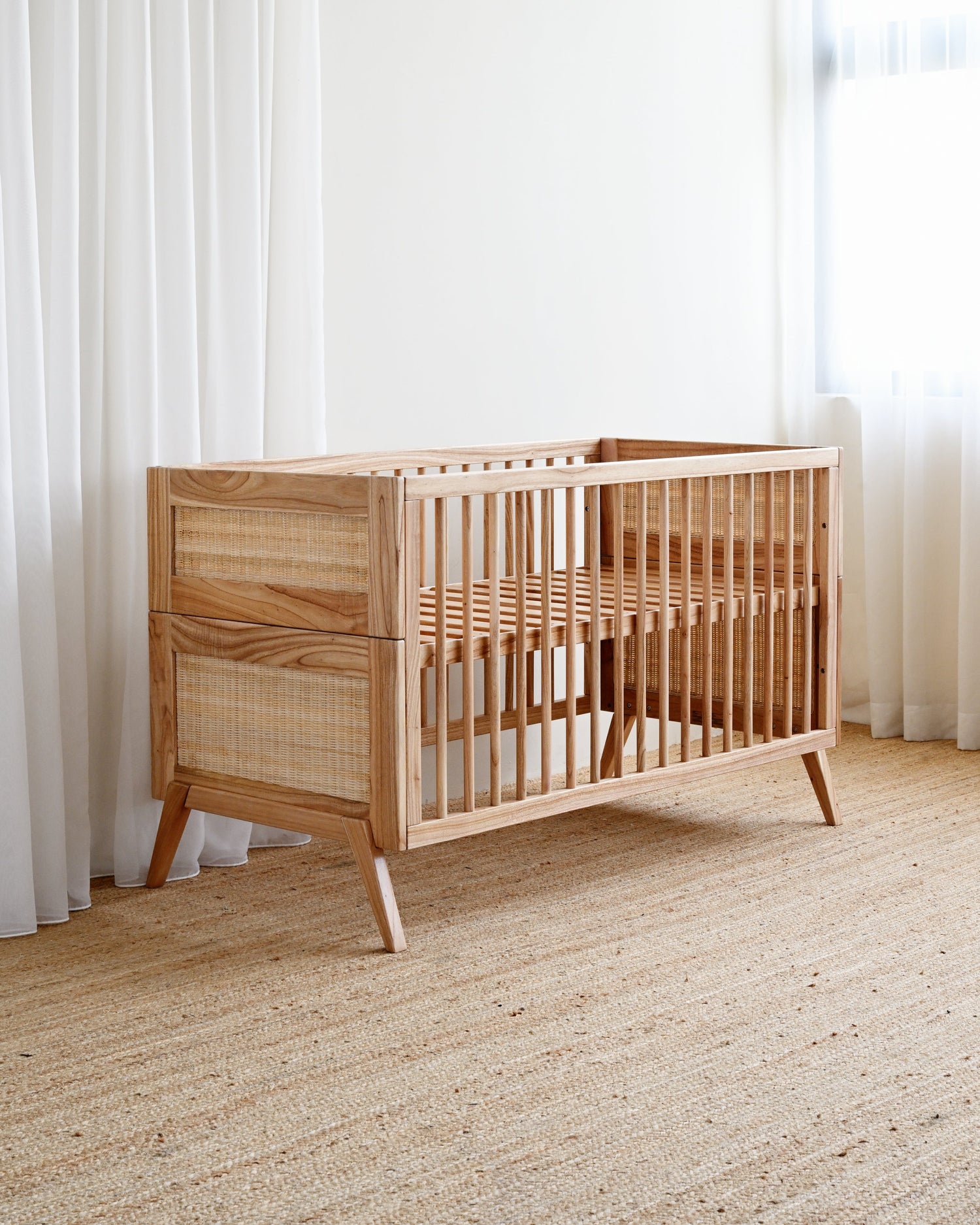 Wooden crib in a room with light-colored walls and carpet