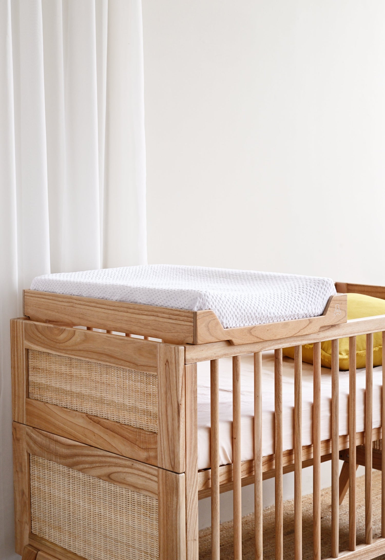 Wooden crib with a white mattress in a minimalistic room.