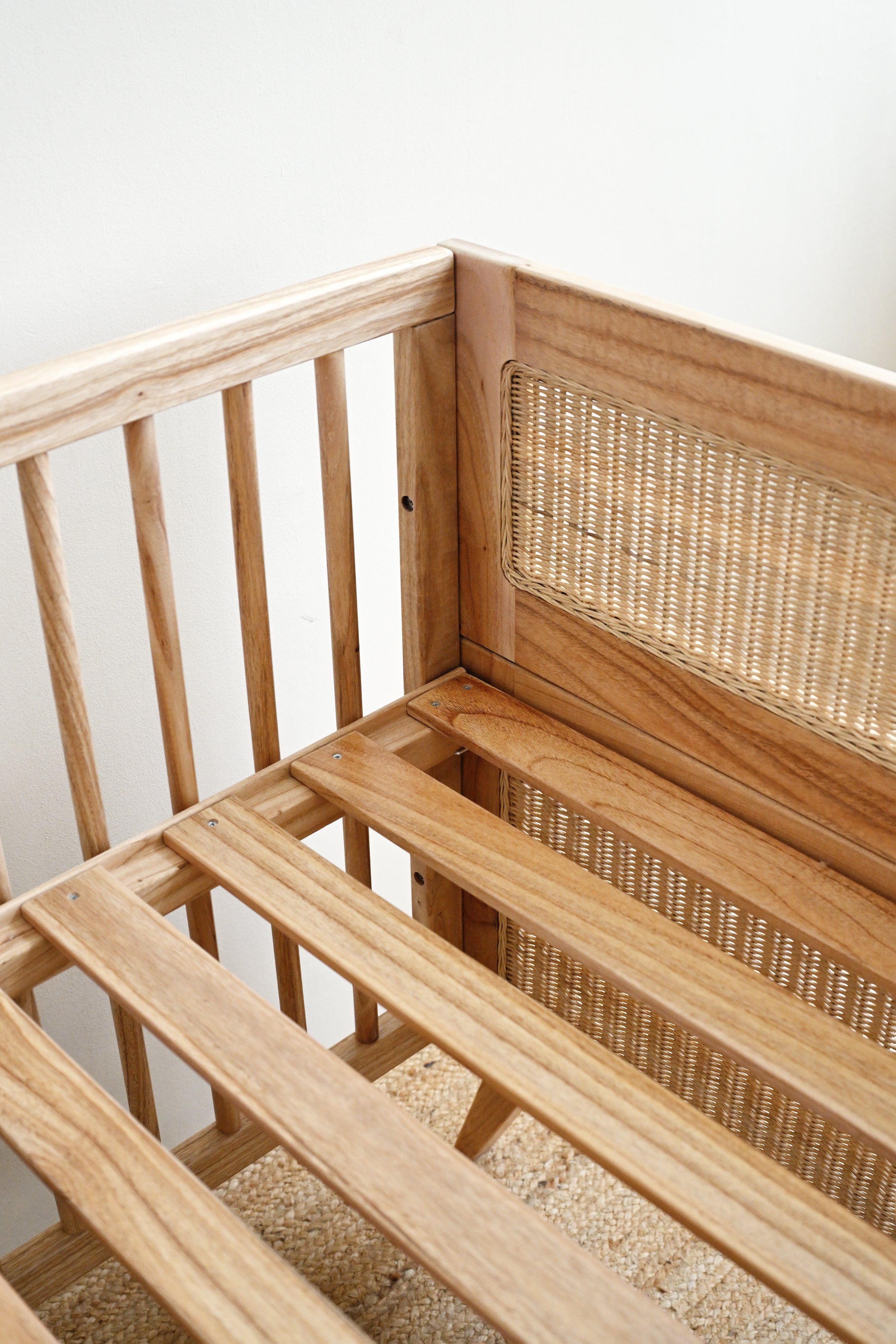 Wooden crib with wicker backrest against a white wall