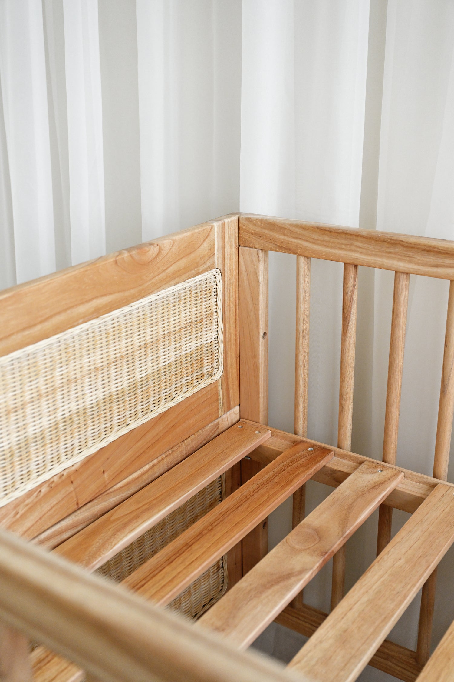 Wooden bench with woven backrest against a white curtain background