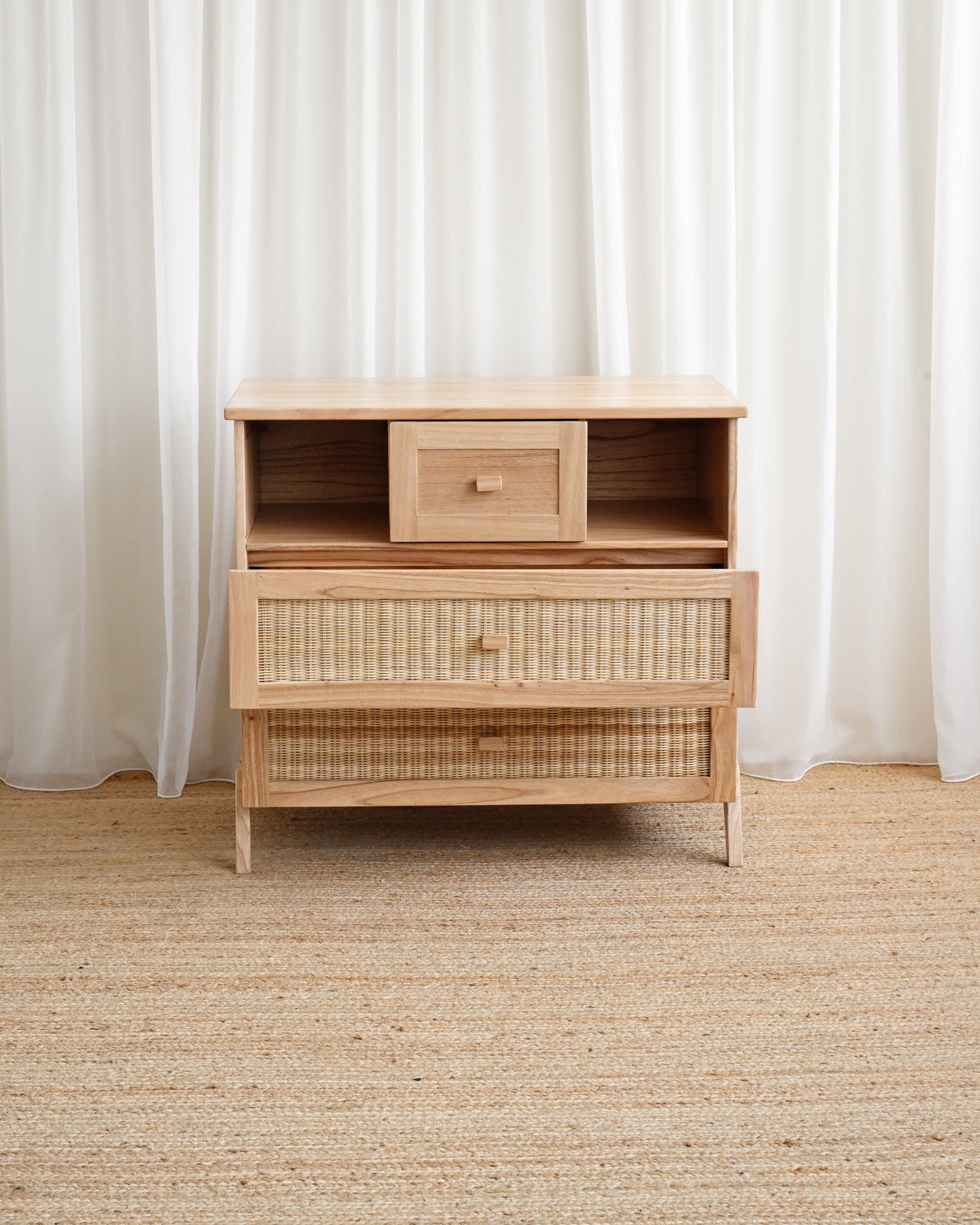 Wooden dresser with woven design against white curtains