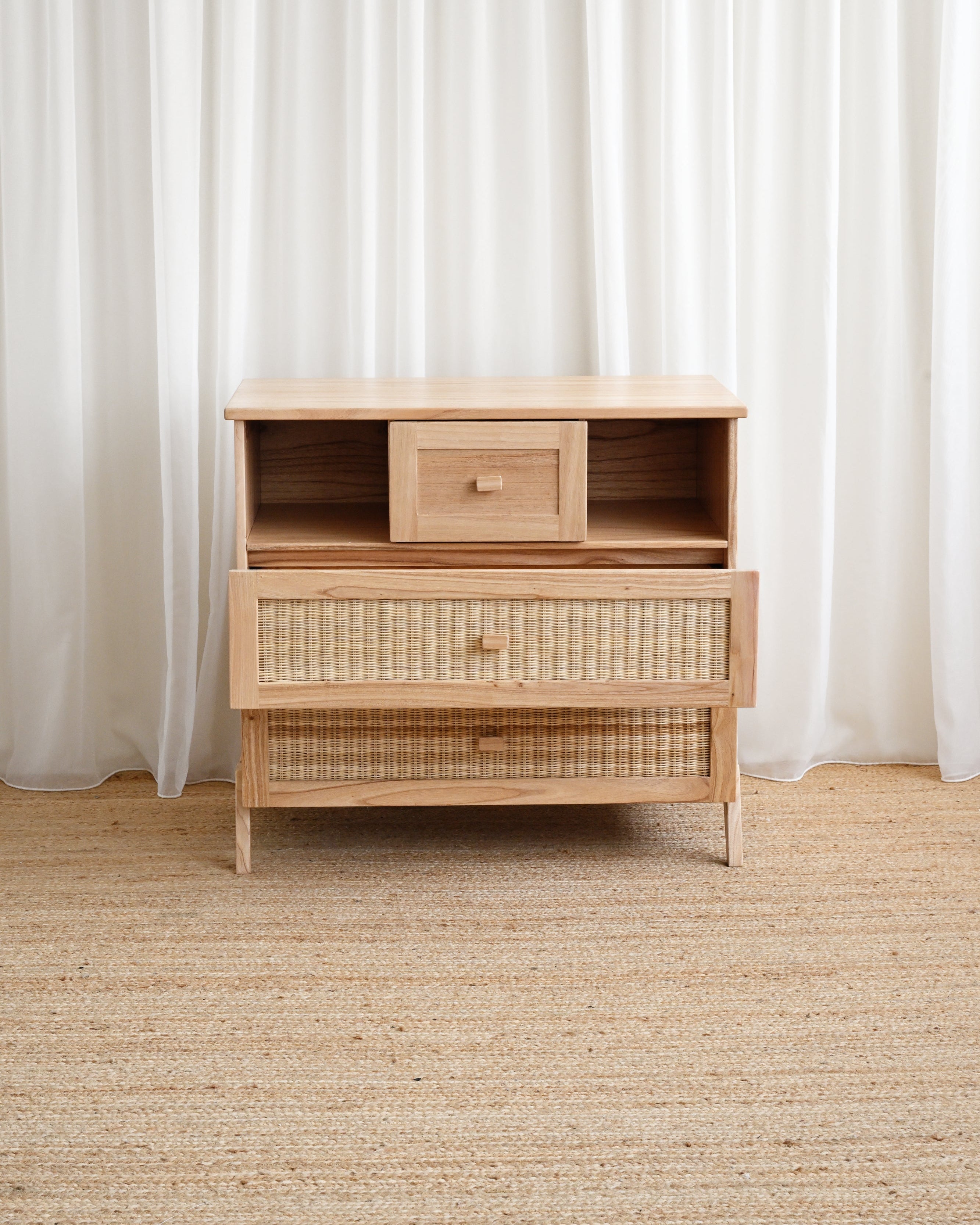 Wooden dresser with woven design against white curtains