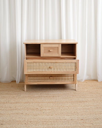 Wooden dresser with woven design against white curtains