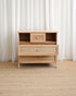 Wooden dresser with woven design against white curtains