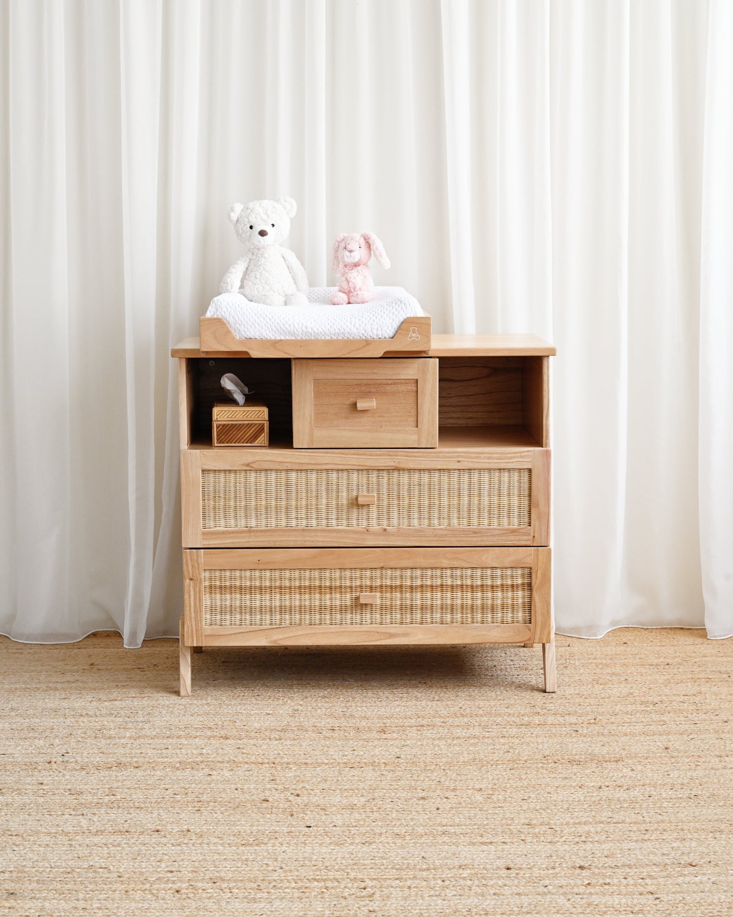 Wooden changing table with toys on top against a white curtain background
