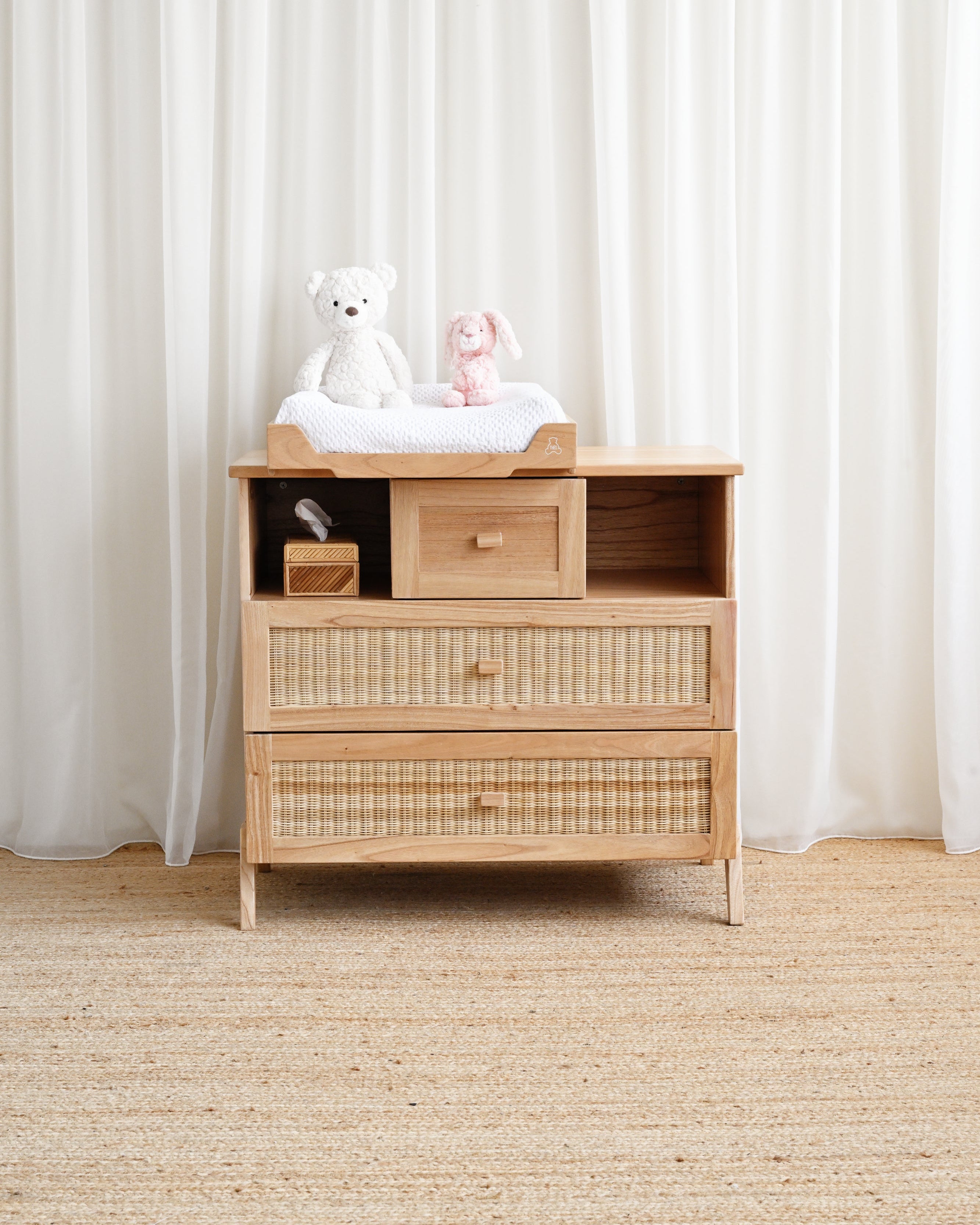 Wooden changing table with toys on top against a white curtain background