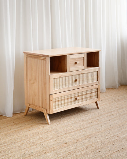 Wooden dresser with woven details against a white curtain background