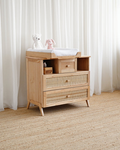 Wooden dresser with wicker drawers against a white curtain background