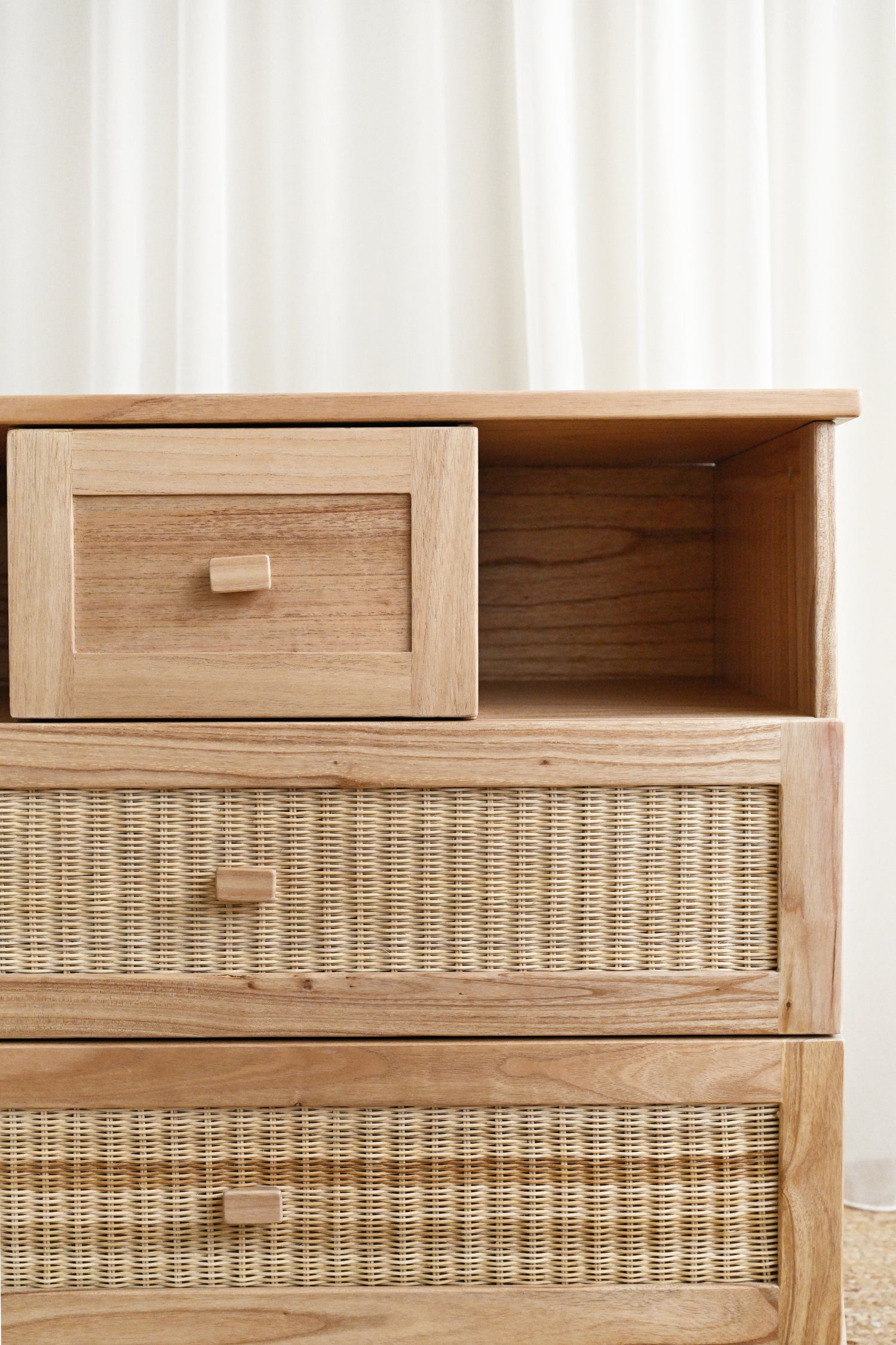 Wooden dresser with wicker drawers against a white wall