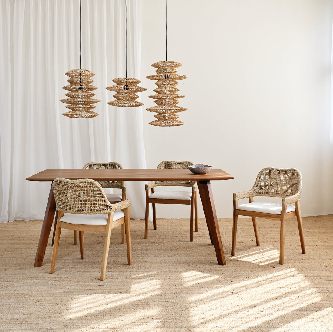 Dining area with wooden table and chairs under pendant lights in a bright room.