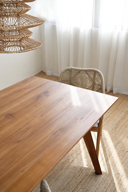 Wooden dining table with wicker chair in a bright room