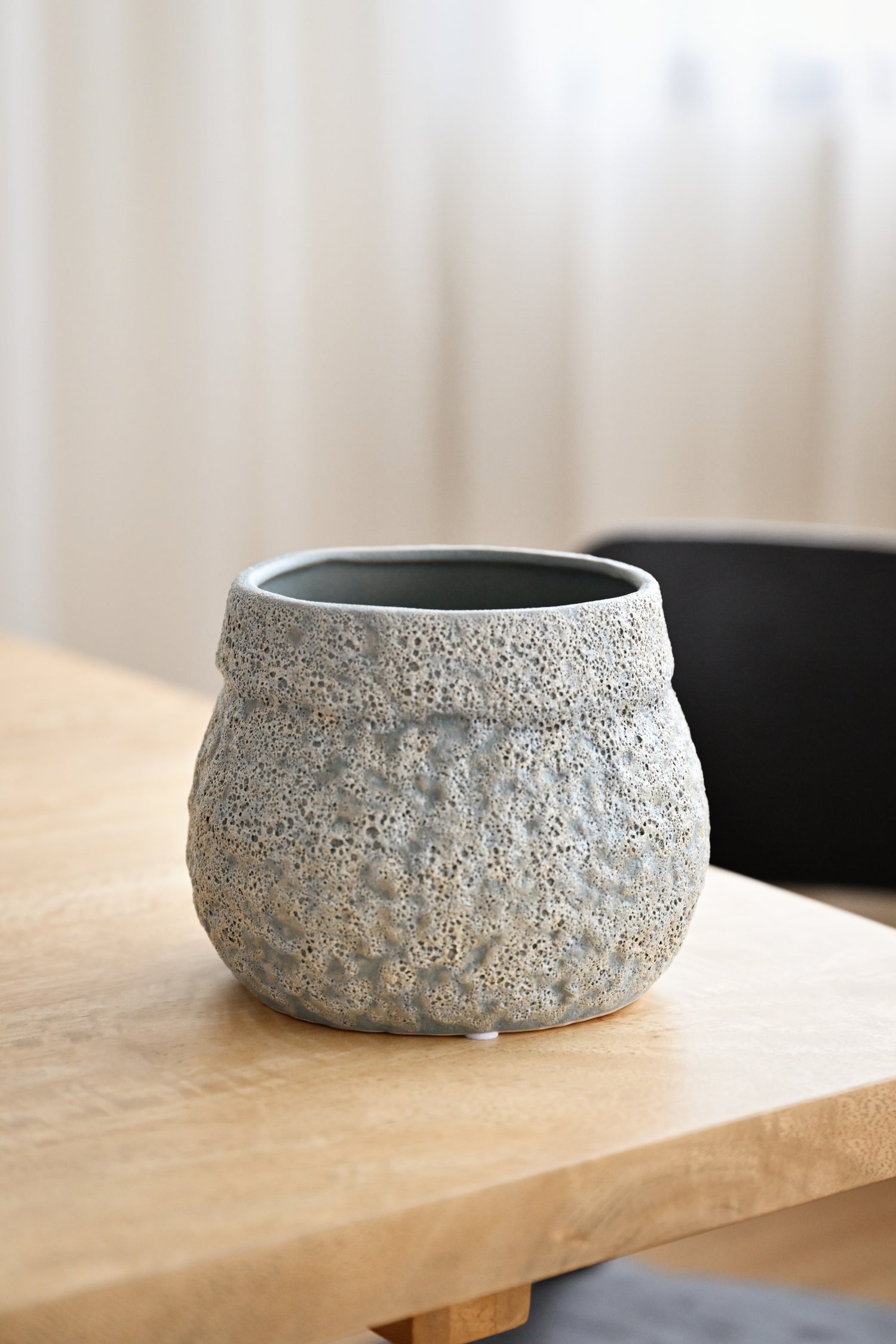 Textured gray pot on a wooden surface with a blurred background