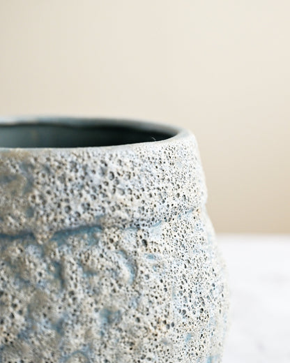 Textured ceramic pot on a neutral background