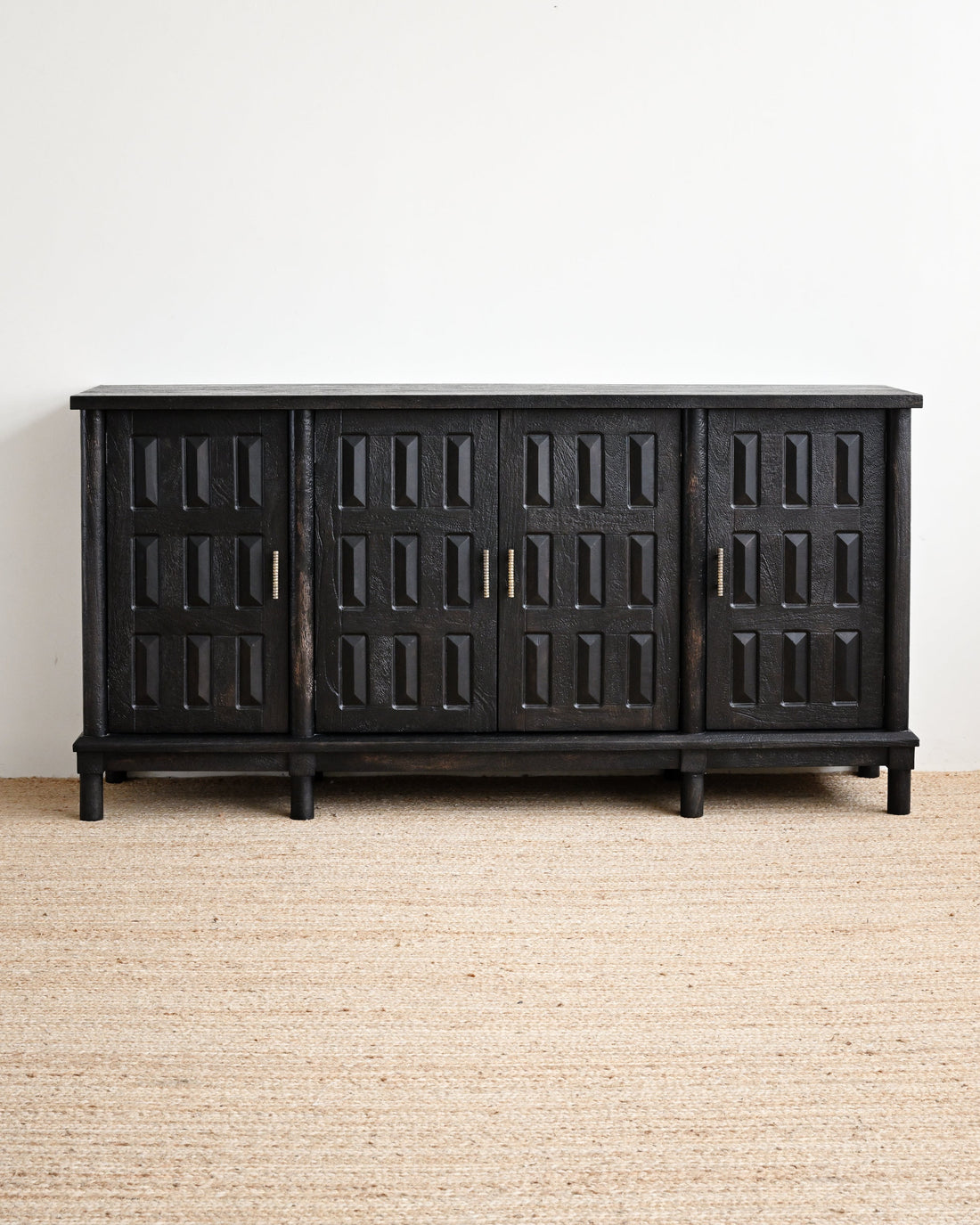 Black wooden sideboard with geometric design on a beige carpet and white wall