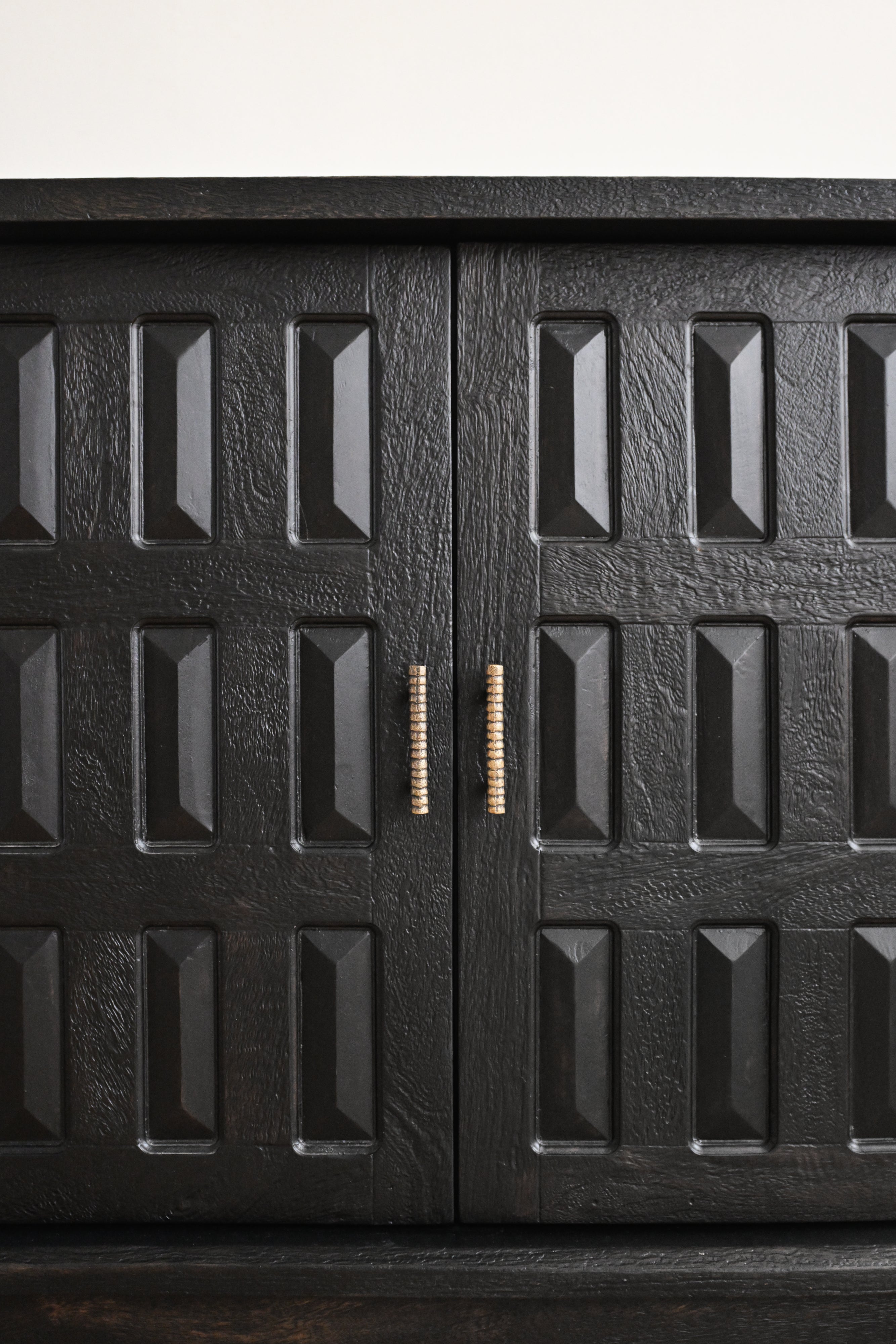 Black metal cabinet with textured surface and decorative handle on a white background