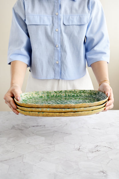 Person holding three ceramic plates on a marble surface