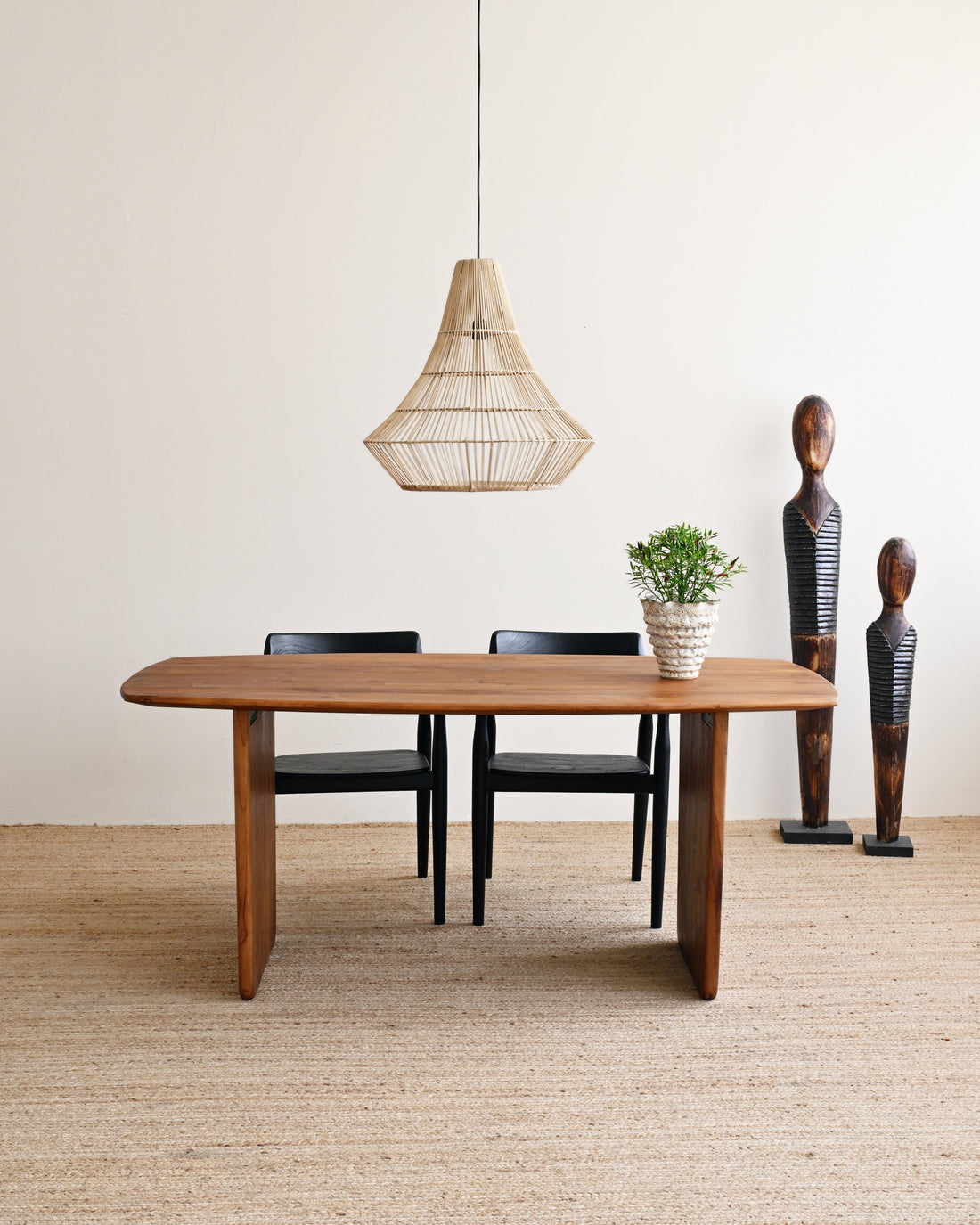 Dining area with wooden table, chairs, and decorative elements in a minimalistic setting.