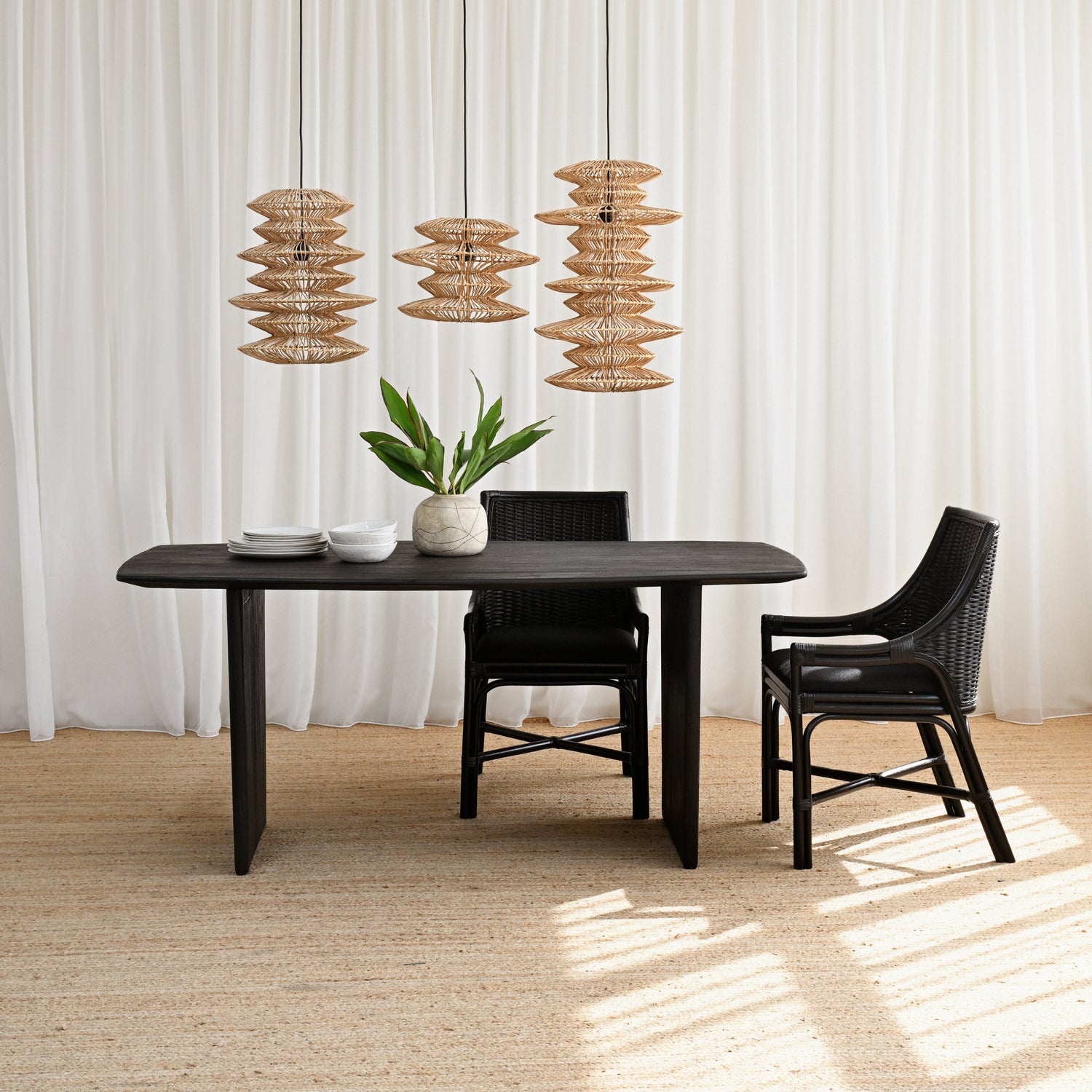Dining table with chairs and decorative elements in a room with white curtains and a textured floor.