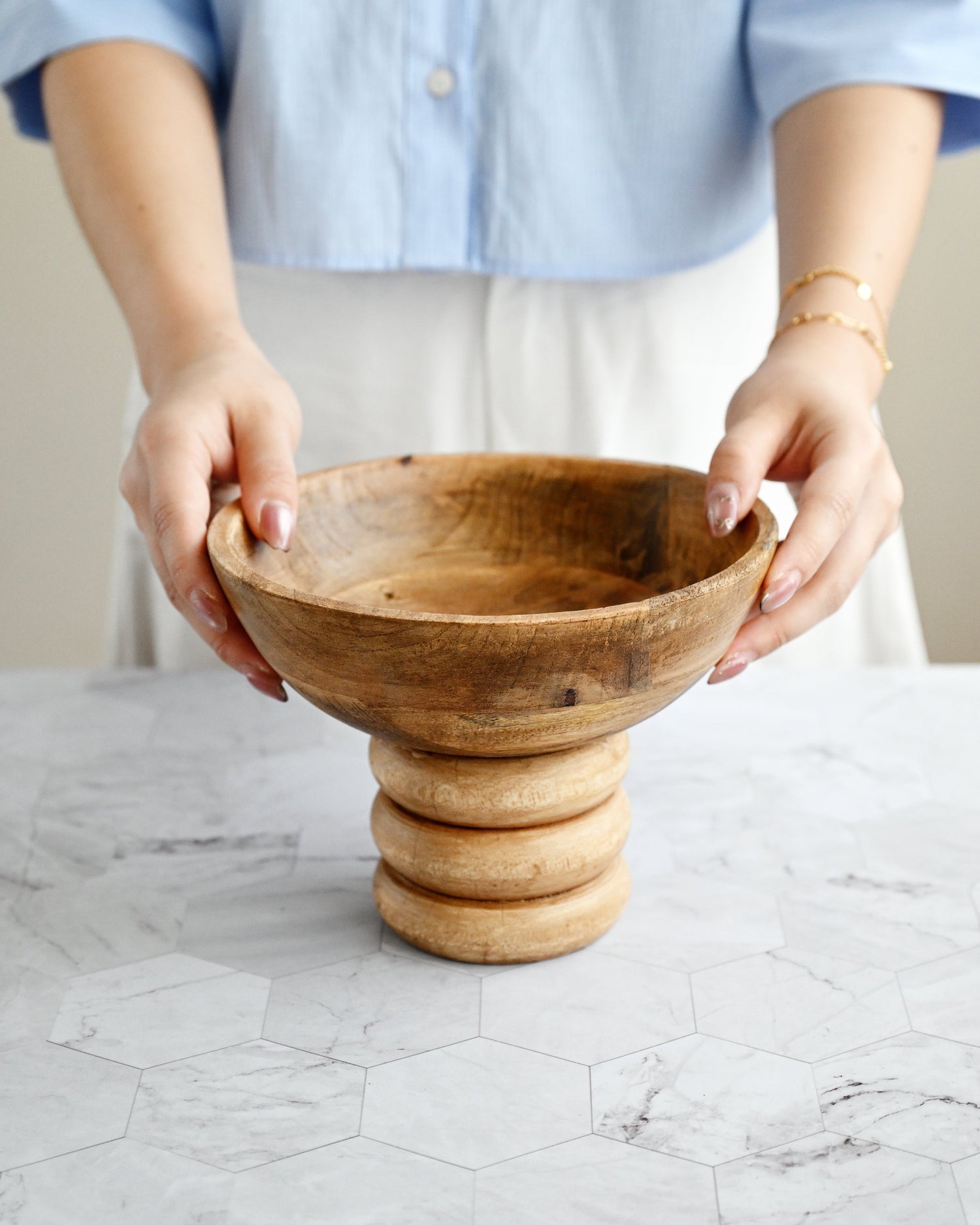 Person holding a wooden bowl on a marble surface