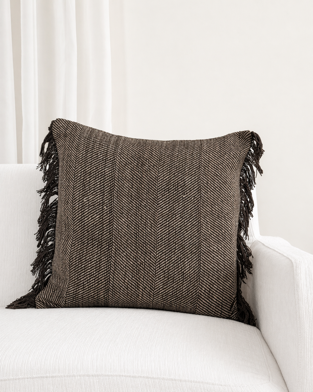 Brown textured pillow with fringes on a white sofa
