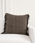 Brown textured pillow with fringes on a white sofa