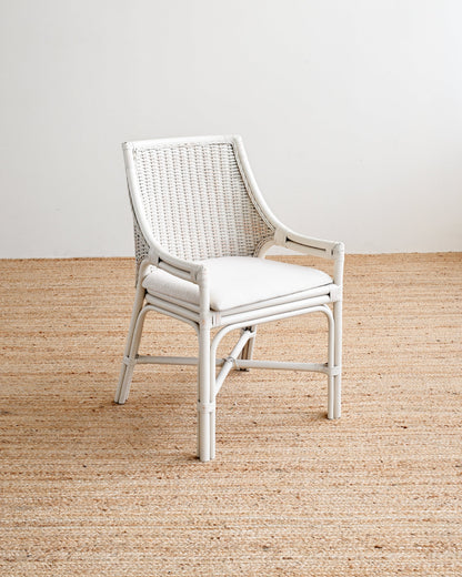 White wicker chair on a wooden floor with a plain white wall background