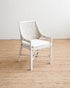 White wicker chair on a wooden floor with a plain white wall background
