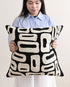 Person holding a black and white patterned pillow against a plain background
