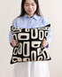 Woman holding a black pillow with white patterns against a plain background