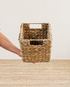 Hand holding a woven basket on a matching woven surface