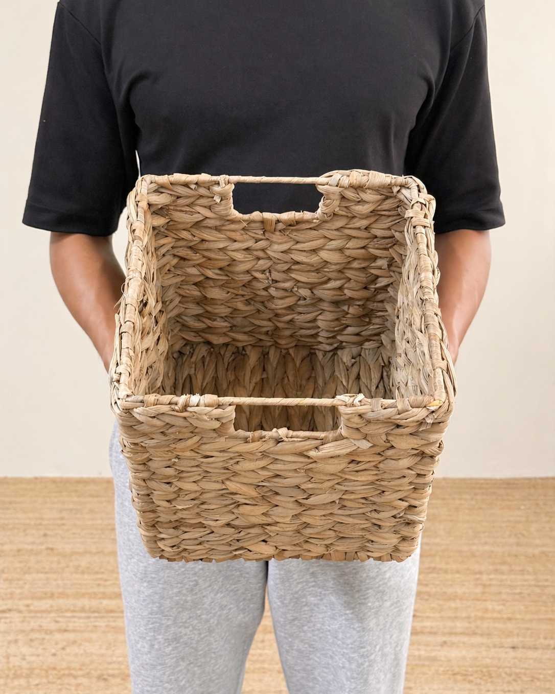 Person holding a woven basket against a neutral background