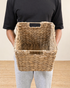 Person holding a woven basket against a neutral background