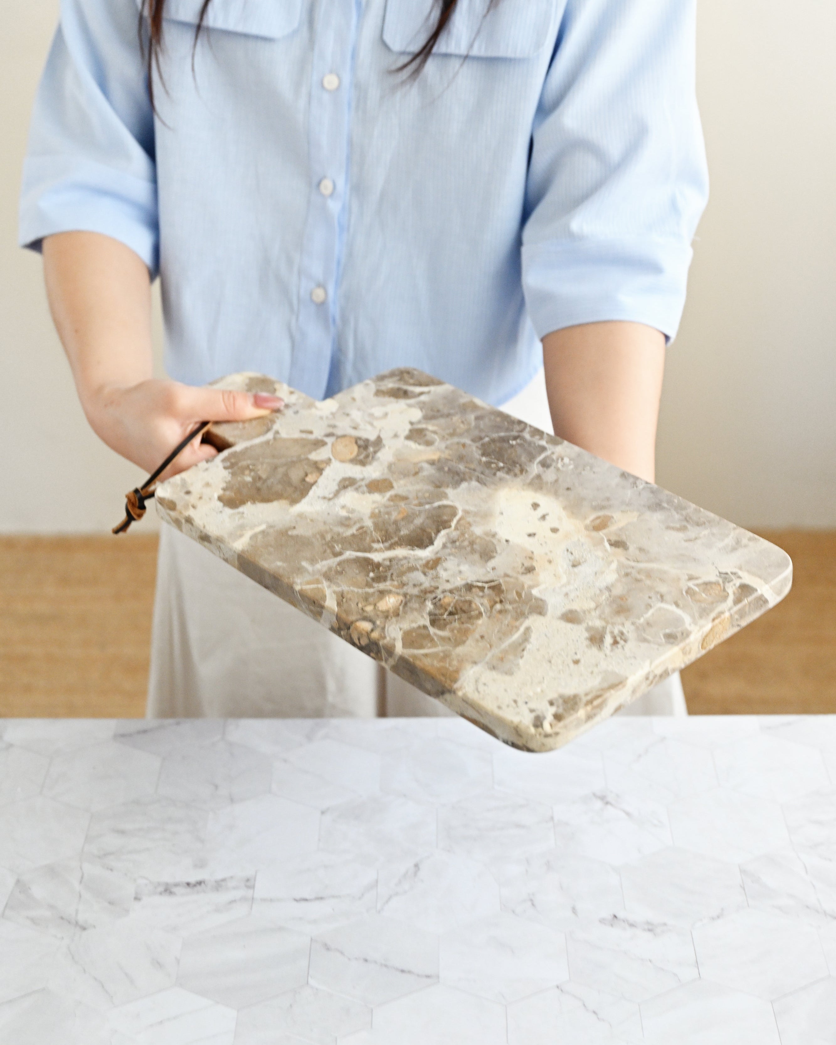 Person holding a stone cutting board with a plain background