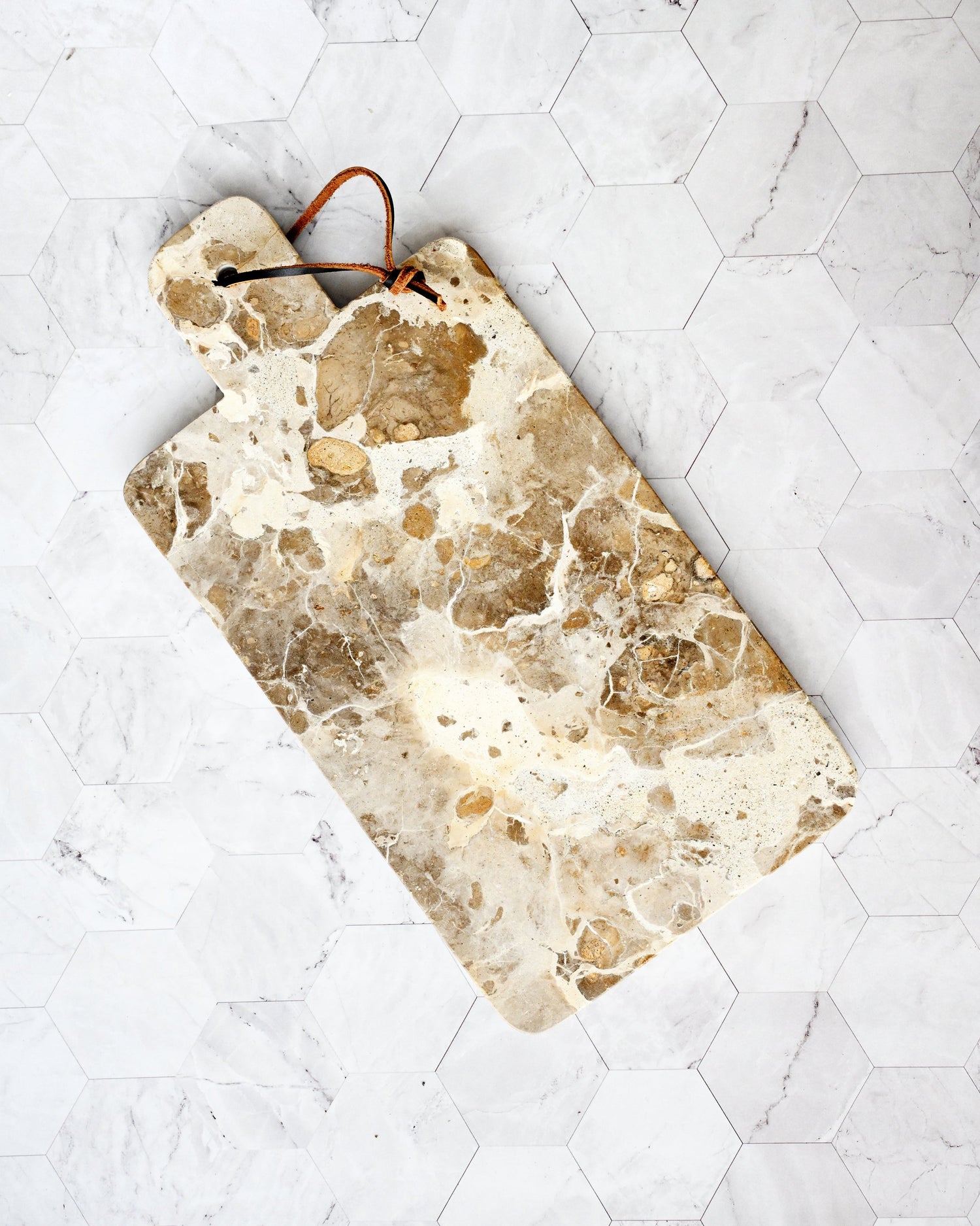 Marble-patterned cutting board on a white tiled surface