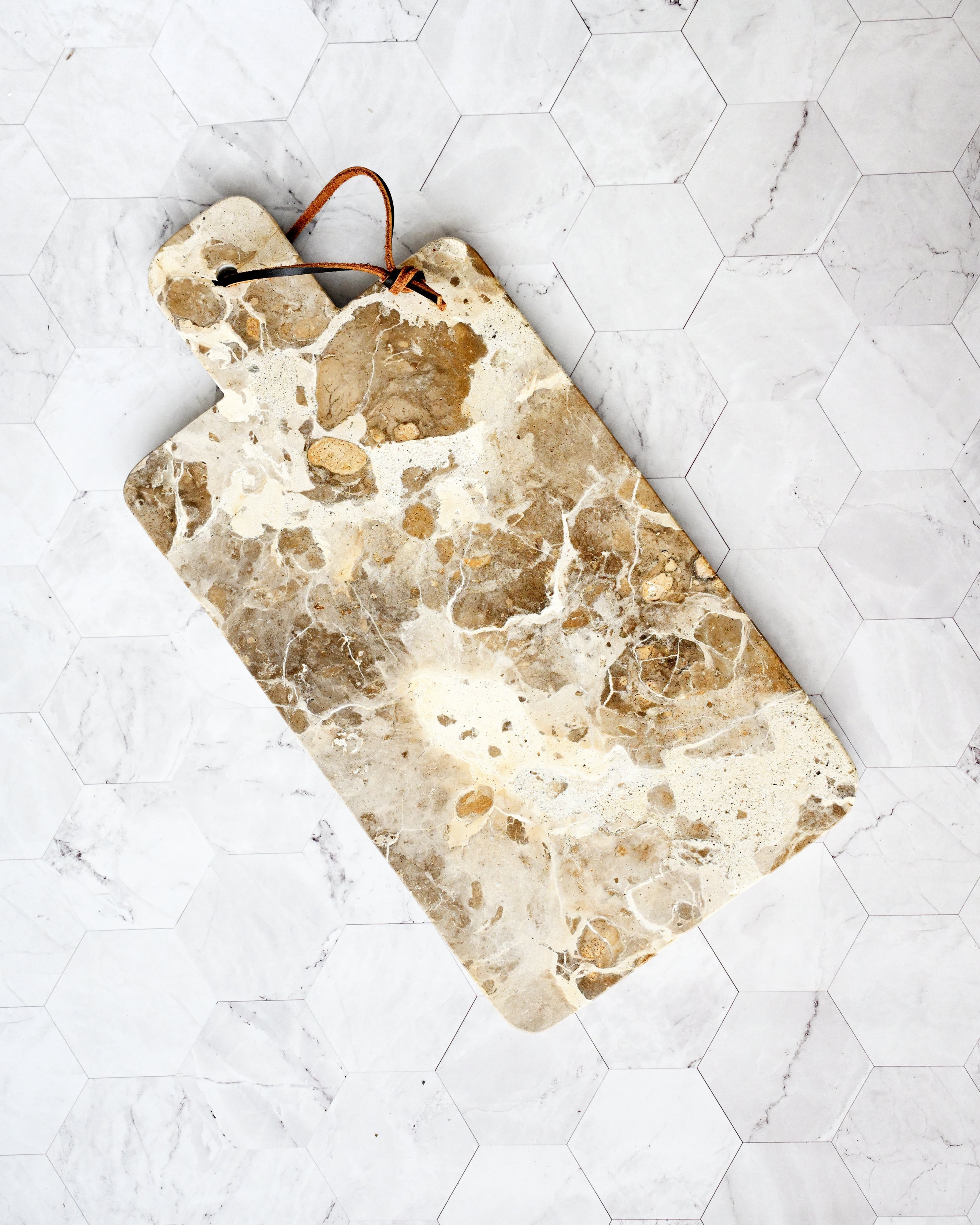 Marble-patterned cutting board on a white tiled surface