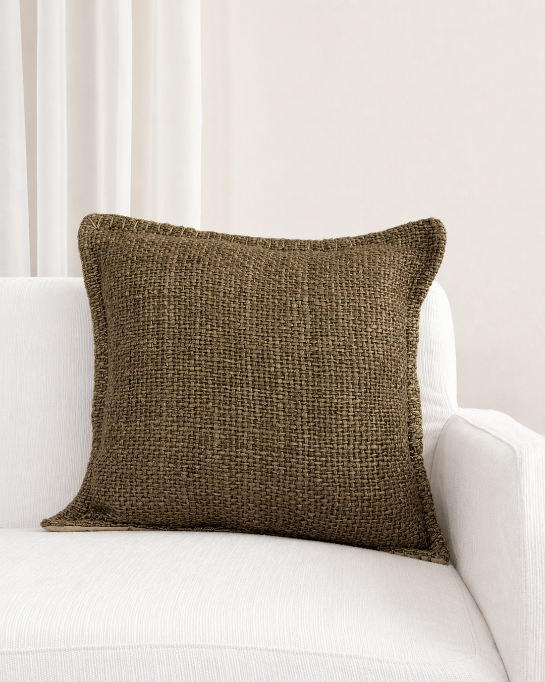 Brown textured pillow on a white sofa with a neutral background
