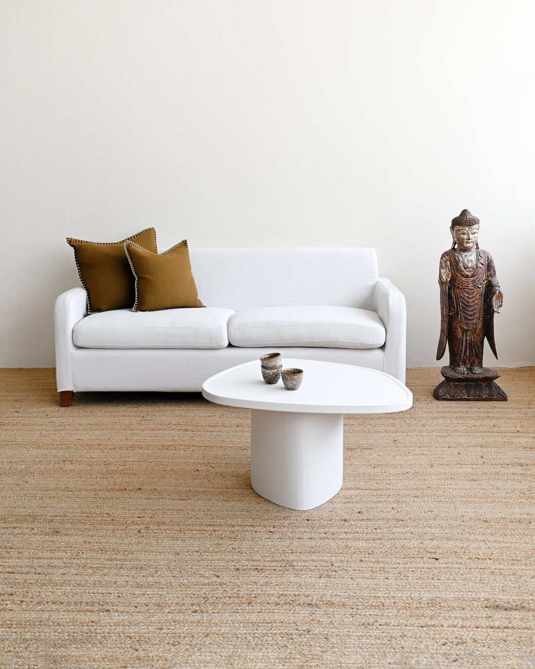 Modern living room with a white sofa, coffee table, and decorative items.