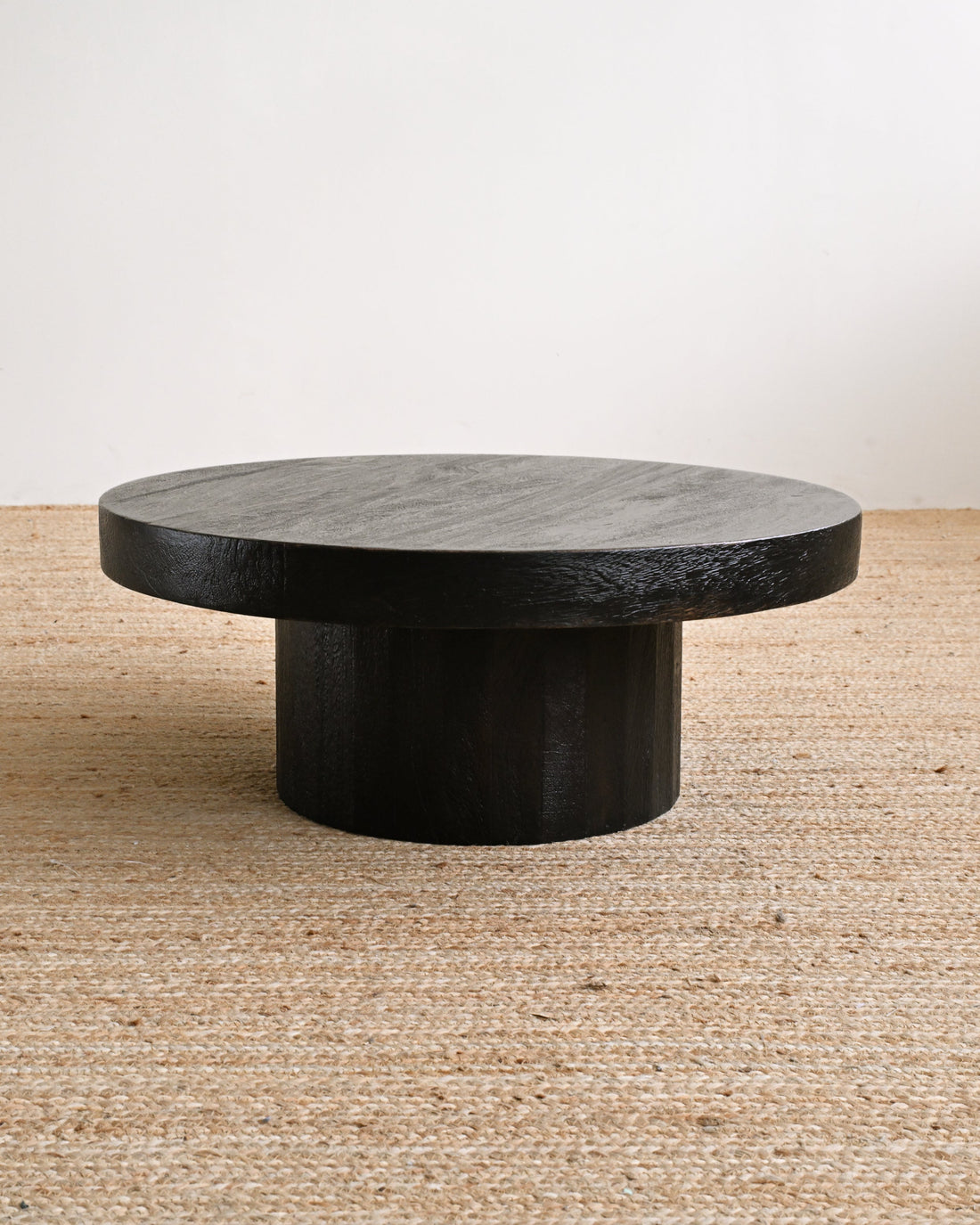 Round stone coffee table on a textured floor with a neutral background