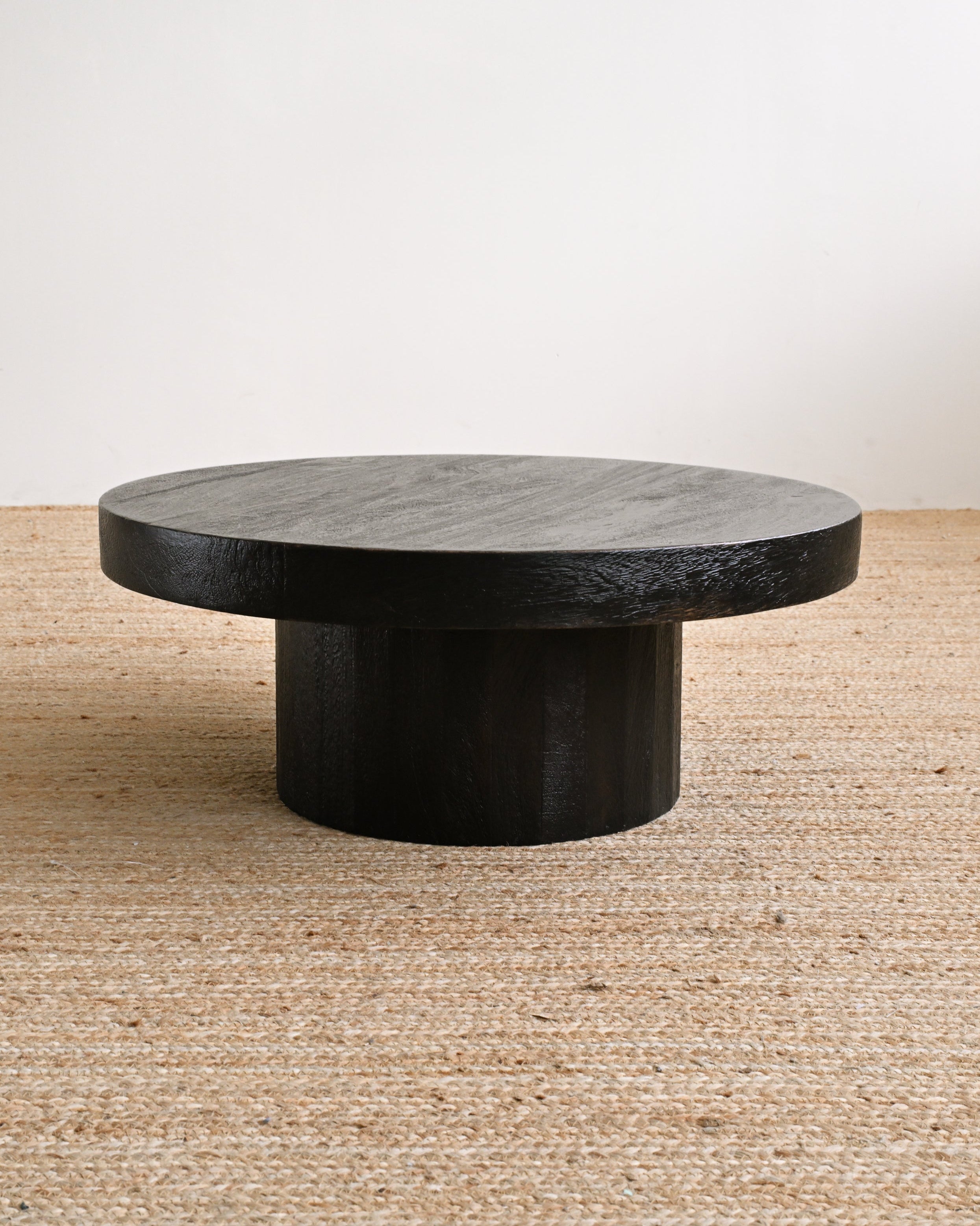 Round stone coffee table on a textured floor with a neutral background