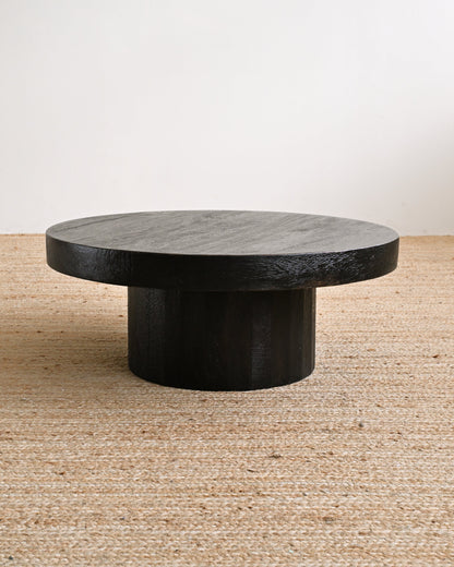 Round stone coffee table on a textured floor with a neutral background