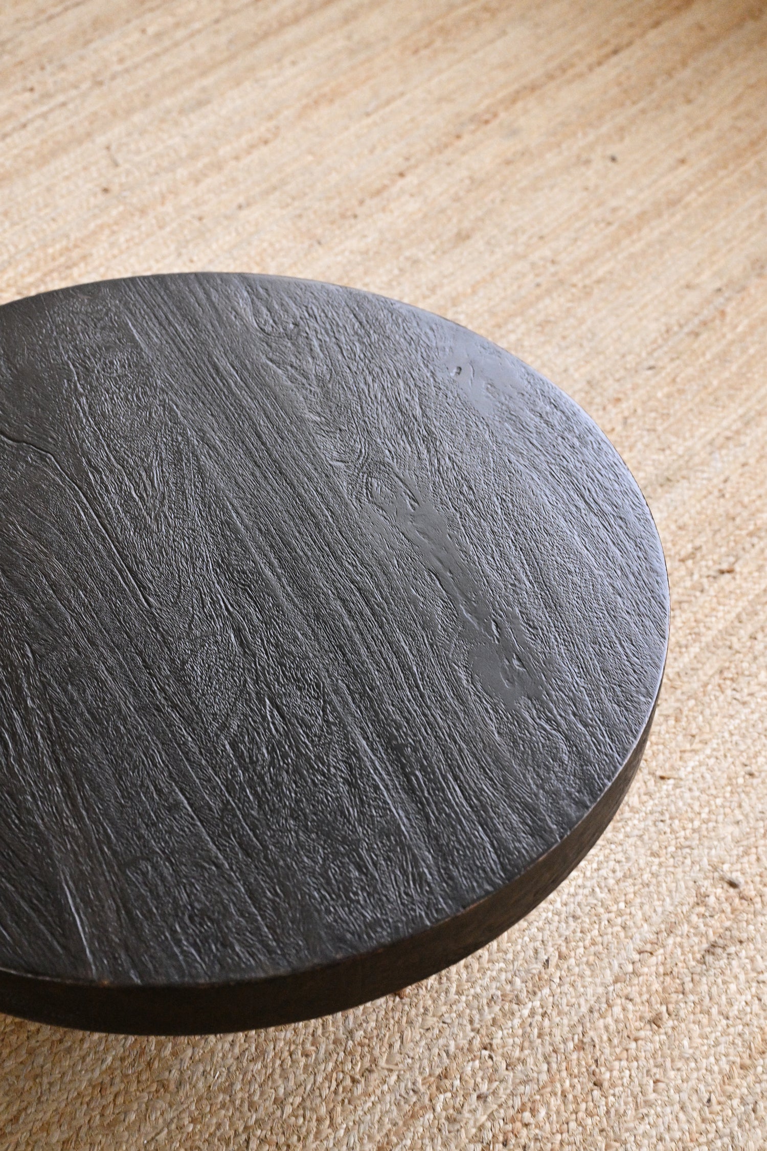 Round black stone coaster on a beige surface