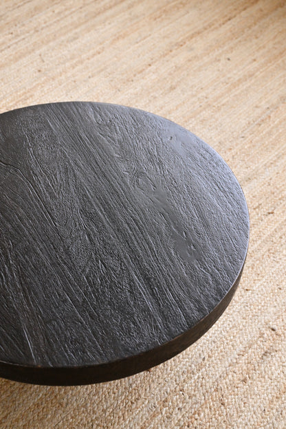 Round black stone coaster on a beige surface