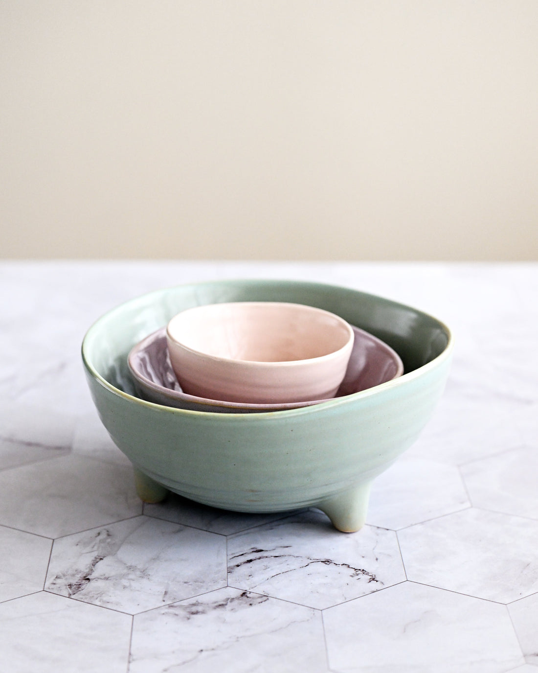Set of ceramic bowls in green and pink on a marble surface with a neutral background