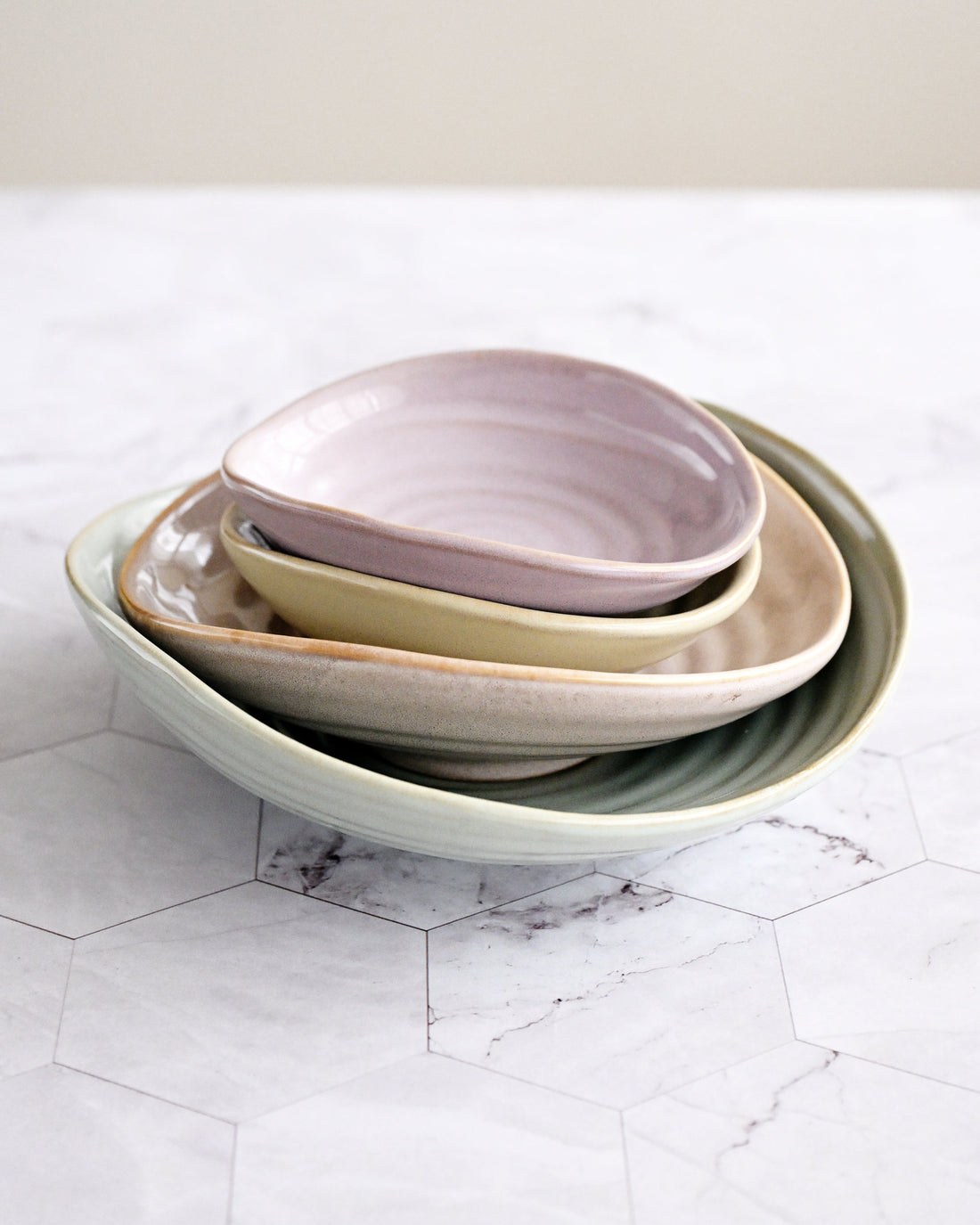Stack of ceramic bowls in pastel colors on a marble surface