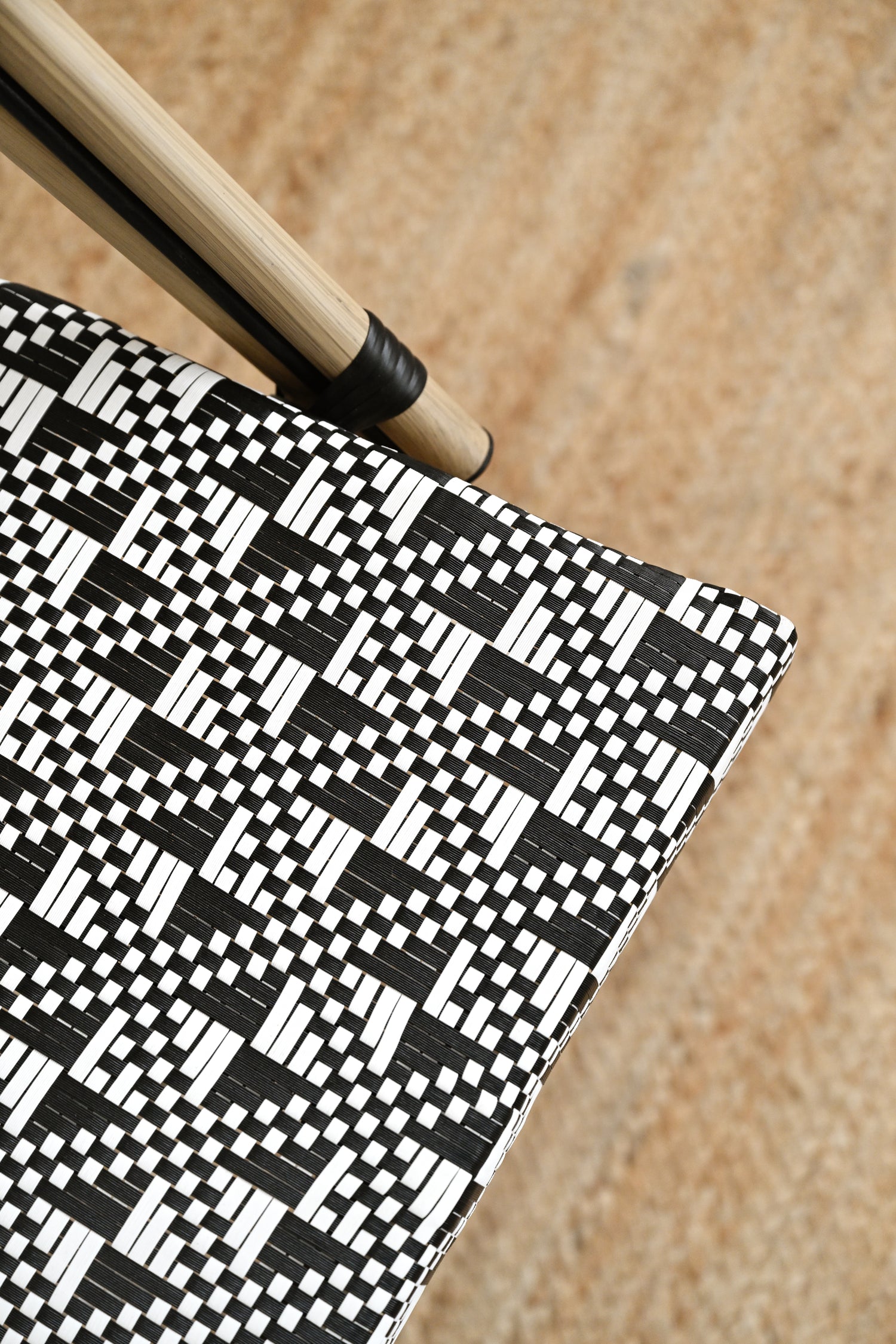 Black and white patterned object with a wooden stick on a beige background