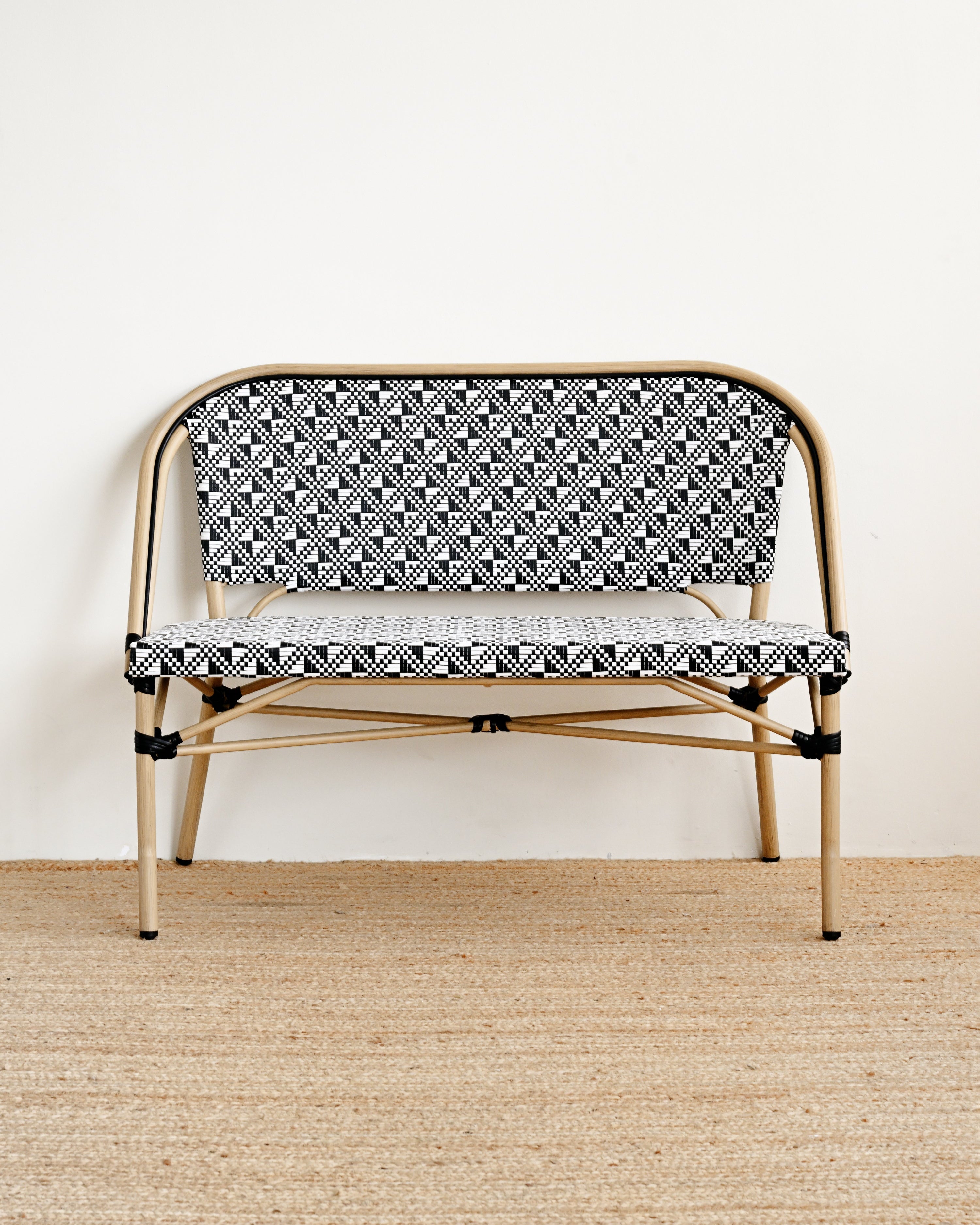 Small bench with black and white patterned seat on a beige floor.