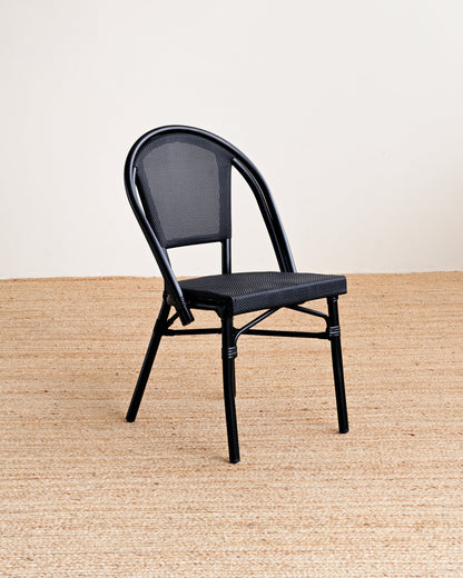 Black metal chair on a beige rug with a white wall background